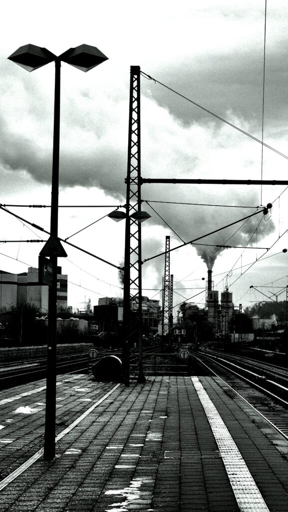 Schwarz-weiß Photo mit Blick auf Industrielandschaft. Ein Schornstein raucht. 